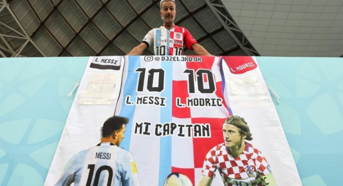 在日本和克罗地亚的16强比赛前,一名球迷拿着梅西和卢卡-莫德里奇的半身球衣和横幅。
